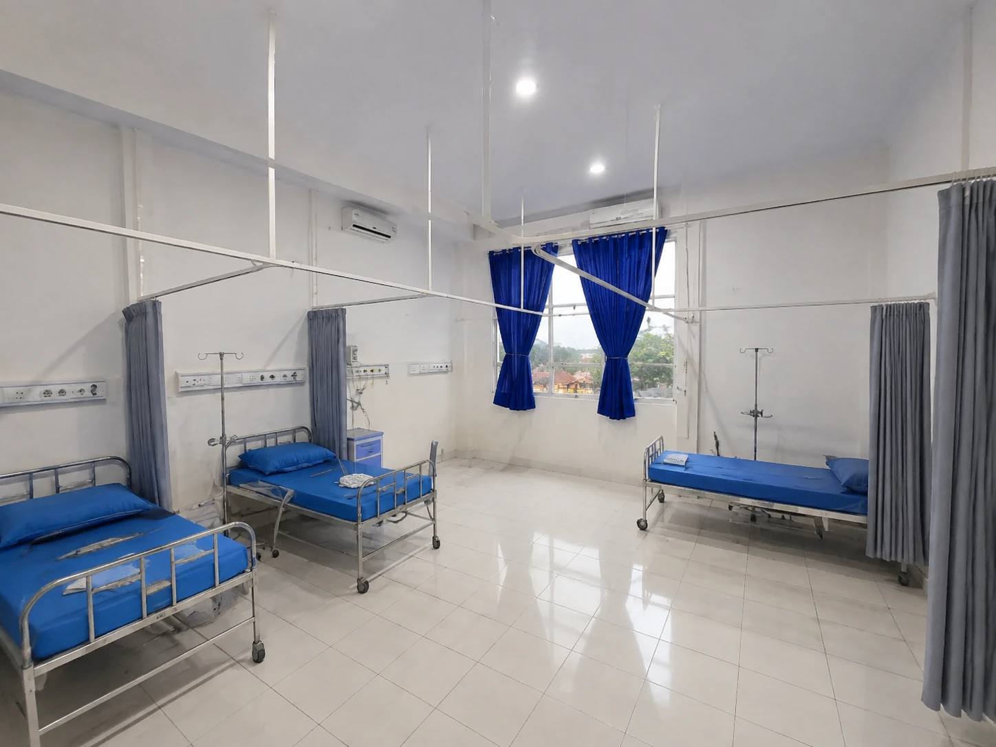 Ruang rawat inap Utama Mawar Biru dengan beberapa tempat tidur dan tirai privasi