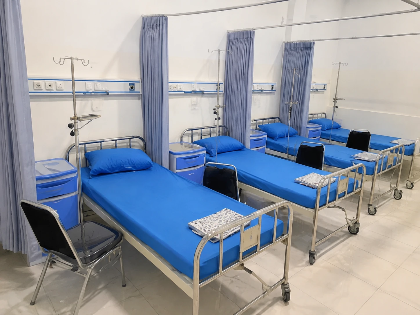 Ruang rawat inap Utama Mawar Pink dengan beberapa tempat tidur dan tirai privasi